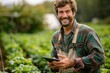 © BOONJUNG - A farmer smiling using a tablet to monitor plant growth on a farm, Technology in agriculture