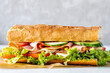 Big sandwich with lettuce, tomatoes prosciutto cucumber and cheese close up on white background