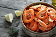 Fresh fried shrimps in a wooden bowl with lemon slices on a wood background top view