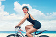 A joyful young woman in a swimsuit rides a bicycle on a sandy beach, capturing a spirit of freedom, adventure, and enjoying an active outdoor lifestyle