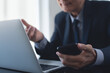 © tippapatt - Asian businessman online meeting via laptop computer by online meeting app from office, video conference. Smiling senior business man, manager making a discussion on teleconference via laptop