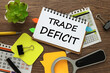 TRADE DEFICIT notepad on the calendar. magnifying glass, notepad. potted plant