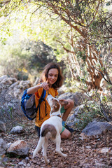 Wall Mural - Little boy with a backpack on a hike. Healthy activity. a cheerful dog plays with a child during a hike, a child plays with a dog while trekking in the forest.