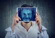 Happy man holding tablet with his face displayed on a screen with binary code 