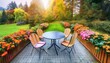 out door chairs with table and lush green garden in autumn or summer; high angle view, close-up of potted seasonal flowers