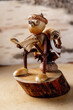 Funny Handicraft - a wooden little man, the head is made of acorns, reads a book made of birch bark while sitting on the toilet