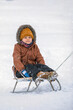 Close-up portrait of happy boy sledding on white snow background