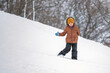 A cute little brave boy traveling on a snow-covered hill during a blizzard