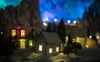 Little decorative cute small houses in snow at night in winter, Christmas and New Year miniature house in the snow at night with fir tree. Holiday concept.