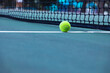 Tennis ball on tennis court with net in background
