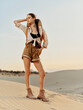 © SHOTPRIME STUDIO - Woman standing on sand dune in desert wearing shorts and shirt on sunny day with clear blue sky