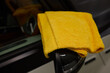 A yellow towel lies on a car hood near an automotive