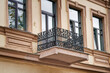 Old balcony with cast iron railing and windows on facade of historic building. Windows and balcony with wrought iron railing. Architectural details of ancient building. Minsk, Revolyutsionnaya street