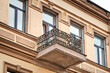 Old balcony with cast iron railing and stucco bas relief on facade wall. Historic building facade. Windows and balcony with wrought iron railing. Architectural details. Minsk, Revolyutsionnaya street
