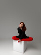 Beauty model woman . Model test portrait with young beautiful fashion model posing on grey background. Red Hair woman in a black blazer and red tights. Natural makeup