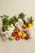 A variety of fresh organic fruits and vegetables, along with vegan meal ingredients, neatly packed in reusable eco cotton bags on a beige background. This setup exemplifies zero waste shopping 