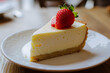 An airy slice of cheesecake with a single delicious strawberry resting on top 