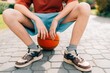 Teen boy tired of playing basketball with ball in summer in the yard