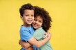 © Maria Vitkovska - Cute brother and sister hugging, looking at camera, posing in studio, isolated on yellow background