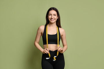 Poster - Happy young woman with measuring tape showing her slim body on green background