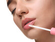 © New Africa - Woman applying lip gloss on white background, closeup