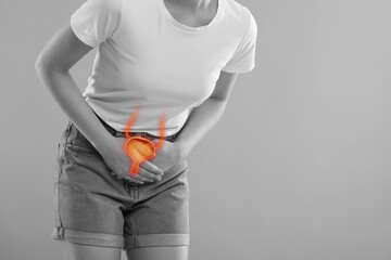 Poster - Woman suffering from cystitis on light grey background, closeup. Illustration of urinary system