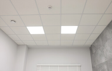 Poster - White ceiling with PVC tiles and lighting indoors, low angle view