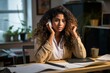 © Molang Visual - A young woman of color sits at her desk looking thoughtful