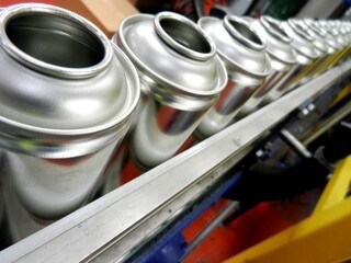 Aerosol production showing aerosol cans on filling belt in busy factory