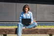 Beautiful woman with laptop working sitting on the bench in the street