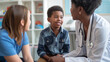 © Natali - Female pediatrician talks to black little boy who is sitting on mother's lap at clinic.