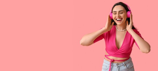 Wall Mural - Smiling young woman in headphones on pink background with space for text