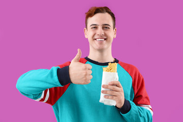 Canvas Print - Young man with tasty sandwich wrap showing thumb-up on purple background