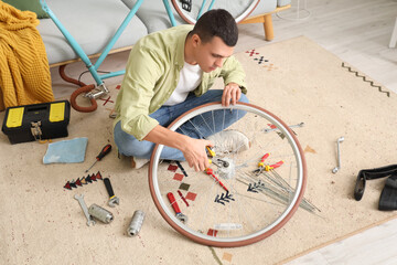 Canvas Print - Young man repairing bicycle wheel at home