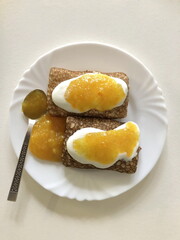 two delicious pancakes with sour cream and orange jam on a plate, view from above