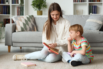 Sticker - Little boy and his mother reading book while sitting on floor at home