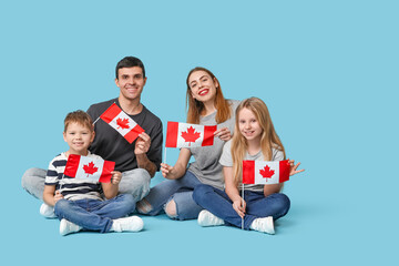 Canvas Print - Happy family with flags of Canada sitting on blue background