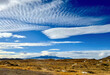 Altocumulus clouds and other cloud formations in deep blue sky hover over Absaroka Mountains in Yellowstone National Park as seen from Cody, Wyoming.