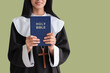 Young nun with Bible on green background