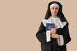 Young nun with Bible on beige background