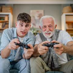 Wall Mural - teenager male and his grandfather senior man play console video game