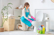 Young woman cleaning toilet bowl in modern bathroom