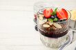 Tasty granola with berries, jam, yogurt and almond flakes in glass on white table, closeup. Space for text