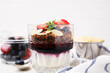 Tasty granola with berries, jam, yogurt and almond flakes in glass on white table