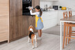 Cute little Asian girl with Beagle dog taking cake from oven in kitchen