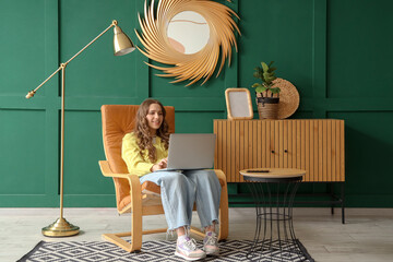 Sticker - Beautiful young woman using laptop in leather armchair at home