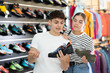 Guy and girl choose climbing shoes together in a sports store