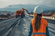 Civil engineer woman supervising road construction. Construction project. Road construction. Crews working on the road. White hard hat and vest. The motorway construction