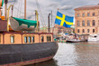 A grand Swedish flag flutters on a boat in a bustling Stockholm harbor, Sweden