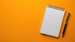 Blank notepad with pen on orange background, top view, space for text
